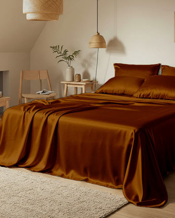 Bedroom with brown satin bedding and wooden furniture.