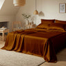 Bedroom with brown satin bedding and wooden furniture.