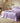 Purple satin bedding set on a bed in a bedroom with wooden furniture and decor.