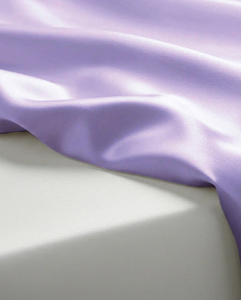Close-up of purple satin fabric on a light gray background