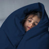 Child wrapped in a blue blanket against a gray background