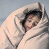 Child wrapped in a beige blanket against a plain background