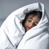 Child wrapped in a white blanket against a gray background